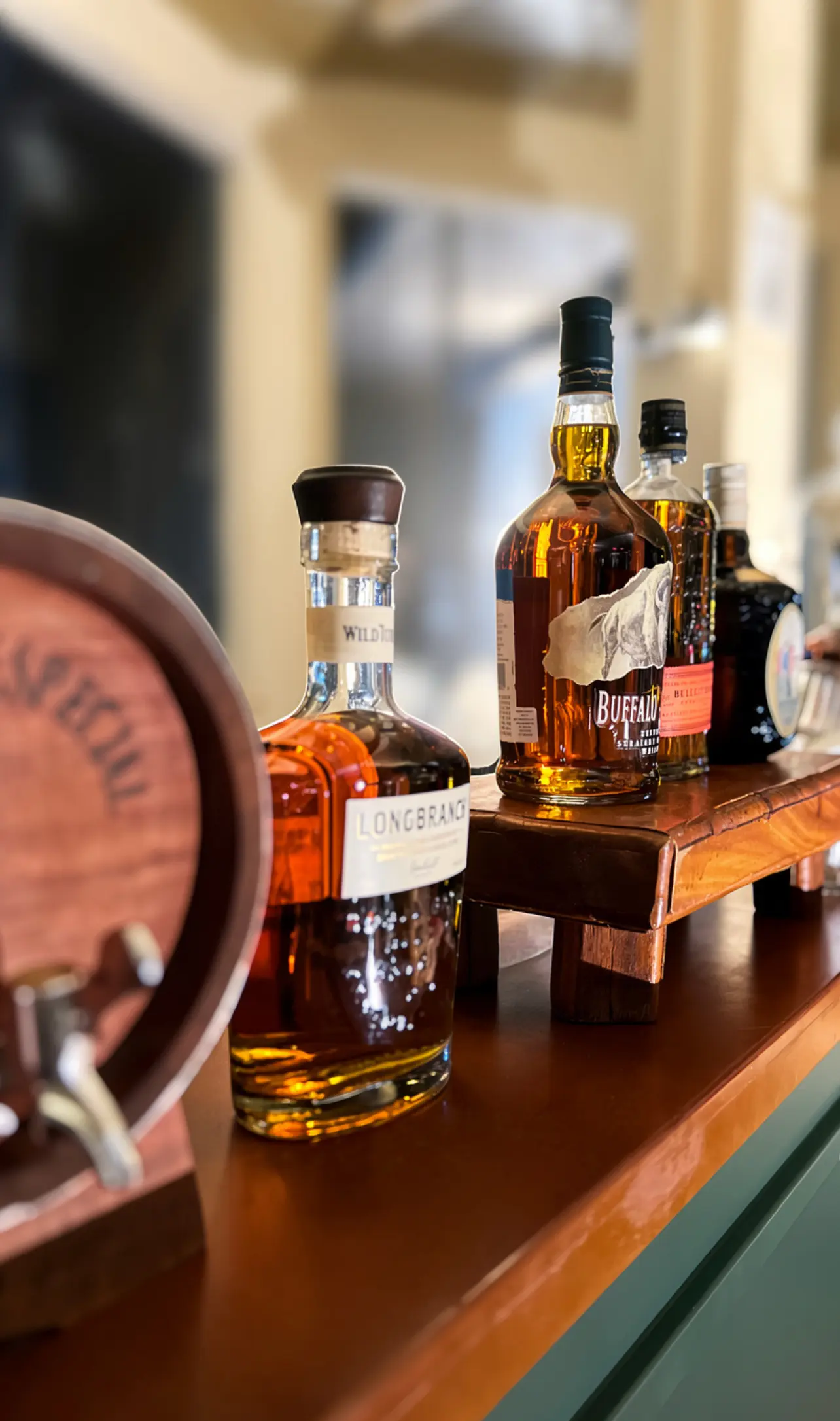 Seleção de whiskys do Bar in Bar sobre balcão de madeira, com barril decorativo em evento